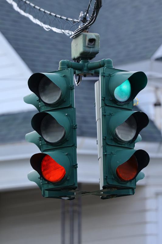 The same hanging signal with the upper right lamp glowing green and the lower left lamp glowing red.