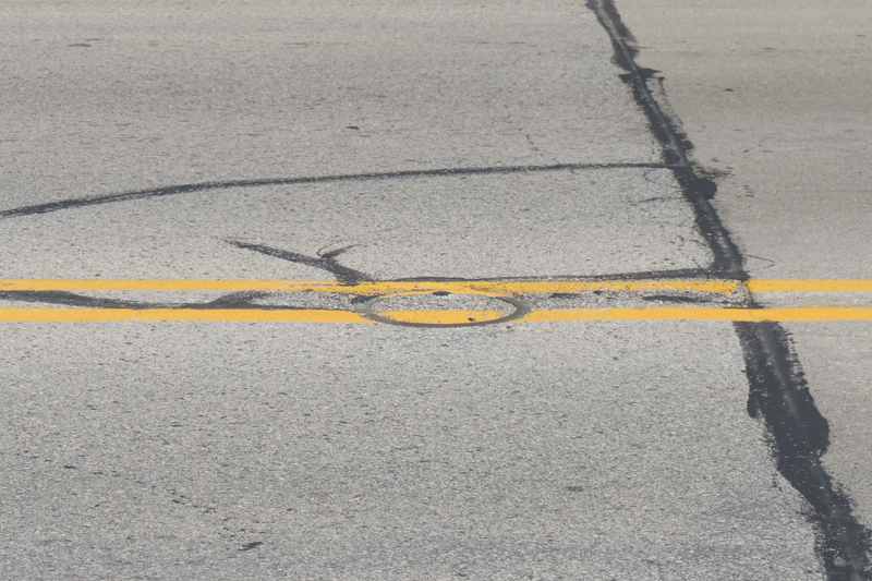 A metal ring surrounds a small section of the double yellow centreline on a paved road.