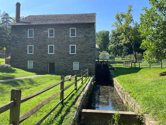 A stone mill and dark wooden waterwheel stand beside a narrow water channel.