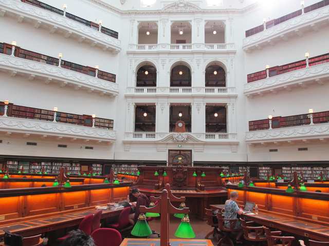 Reading tables and green lamps surround a raised wooden dais beneath tall galleries.