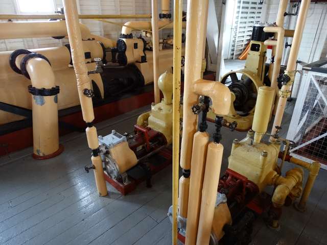 Cream-painted pipes, handwheels and machinery stand on a wooden floor inside the vessel.