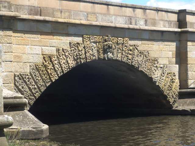 Carved figures and ornamental patterns follow an arch, with horizontal joins across several central stones.