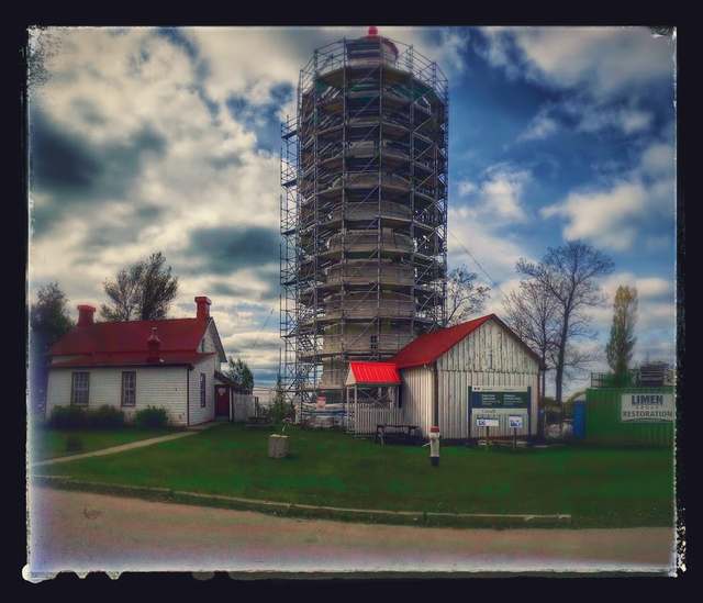 Point Clark lighthouse surrounded by scaffolding, with adjacent buildings inside the photographer’s decorative border.
