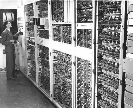 Trevor Pearcey, identified by the archival caption, stands beside tall exposed racks of the CSIR Mk1 computer.