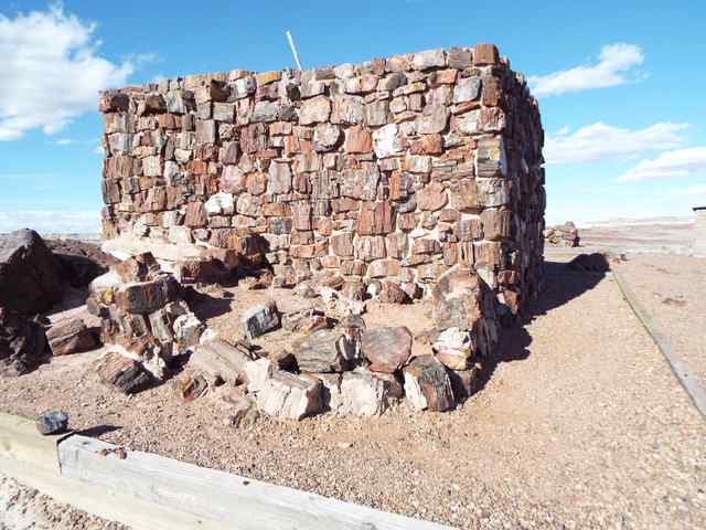 A tall corner of petrified-wood masonry rises beside lower walls and timber ground edging.