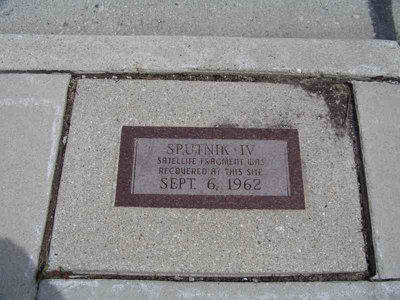 A reddish stone plaque set into a pavement slab reads Sputnik IV and gives the date September 6, 1962.