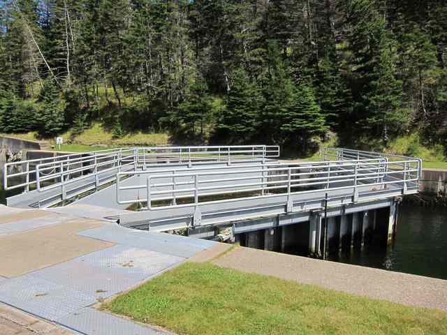 Paired gate leaves and their metal railings span the water beside the concrete lockside.