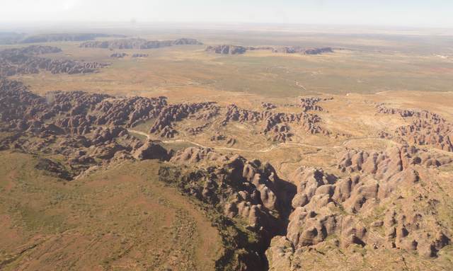 Clusters of rounded sandstone domes and gullies spread across a broad plain, seen from above.