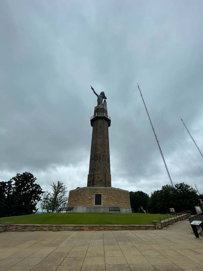 Vulcan above a tall stone tower, seen from the plaza with radio masts nearby.