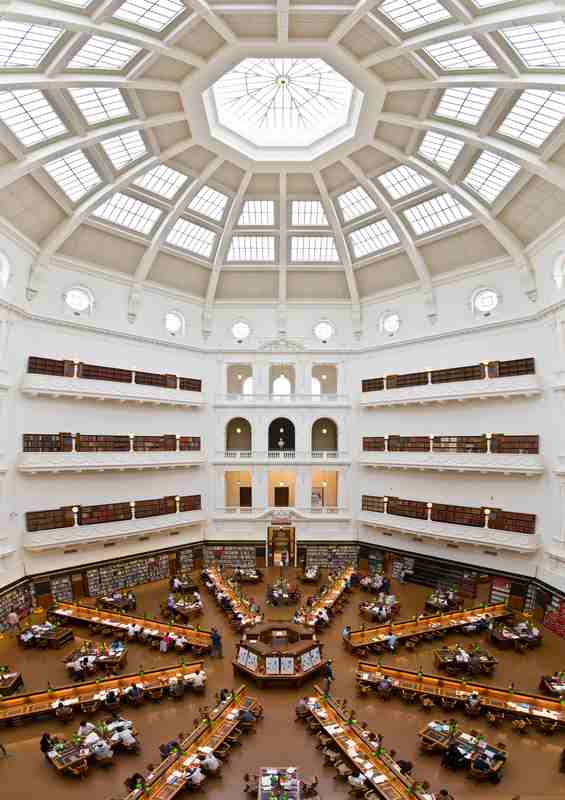 An elevated view over radiating reading desks, wall shelves and stacked galleries beneath the glazed dome.