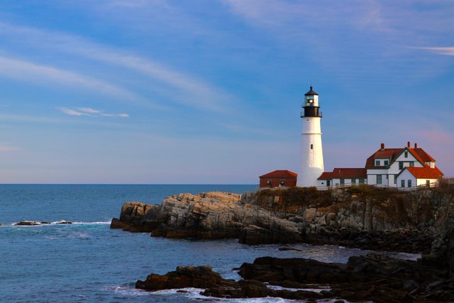 The red-roofed keeper house connects to the white lighthouse through a low range of buildings.