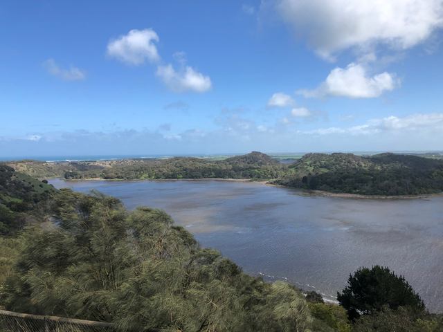 An elevated view over Tower Hill’s lake and wooded hills, with the coast in the distance.