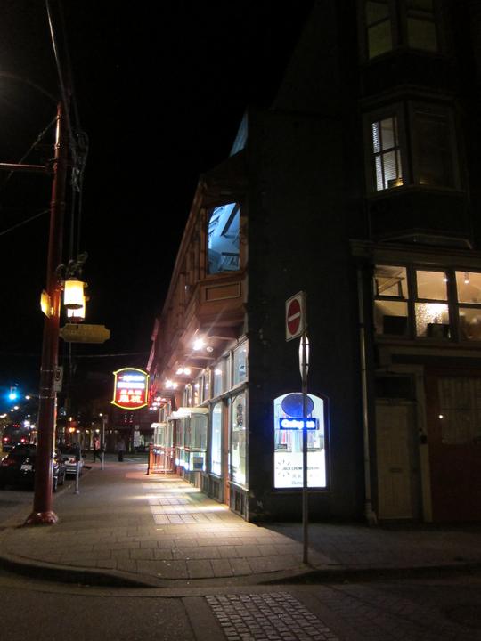 Night view along the building, with projecting upper windows and illuminated glass panels in the pavement.