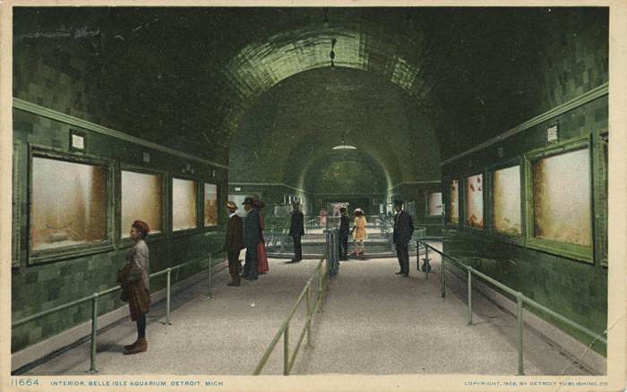 A coloured postcard shows visitors in a long vaulted gallery with tanks along both walls and a railing through the central space.