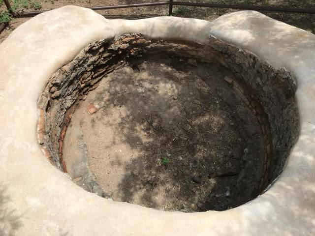 An overhead view shows the kiln’s circular brick interior and pale protective coating around its rim.