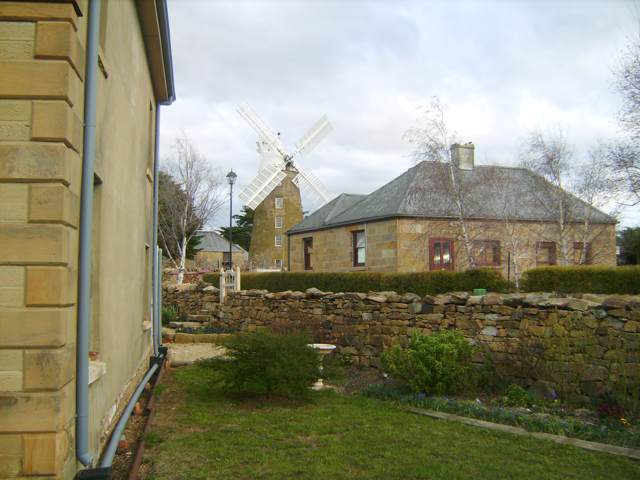 A wider view from High Street shows the windmill behind sandstone buildings and a garden wall.