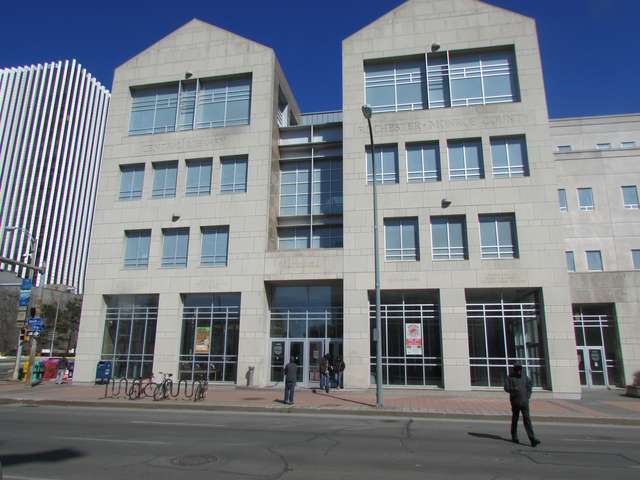 The street-facing pale stone Bausch & Lomb library, with large windows, bicycles and pedestrians outside.