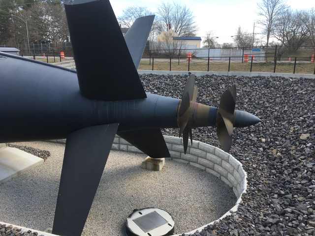 The submarine’s stern fins and two propellers above a gravel-floored dry berth.